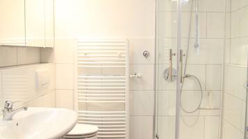 Une salle de bain moderne avec une douche à parois de verre, un lavabo blanc et des toilettes.