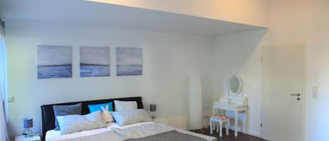 Un dormitorio con una cama grande, un escritorio con una silla y una puerta.