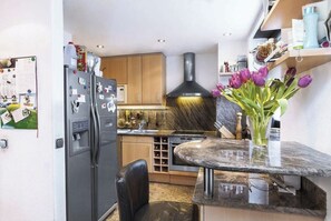 A compact kitchen with a refrigerator, a sink, and a marble countertop.