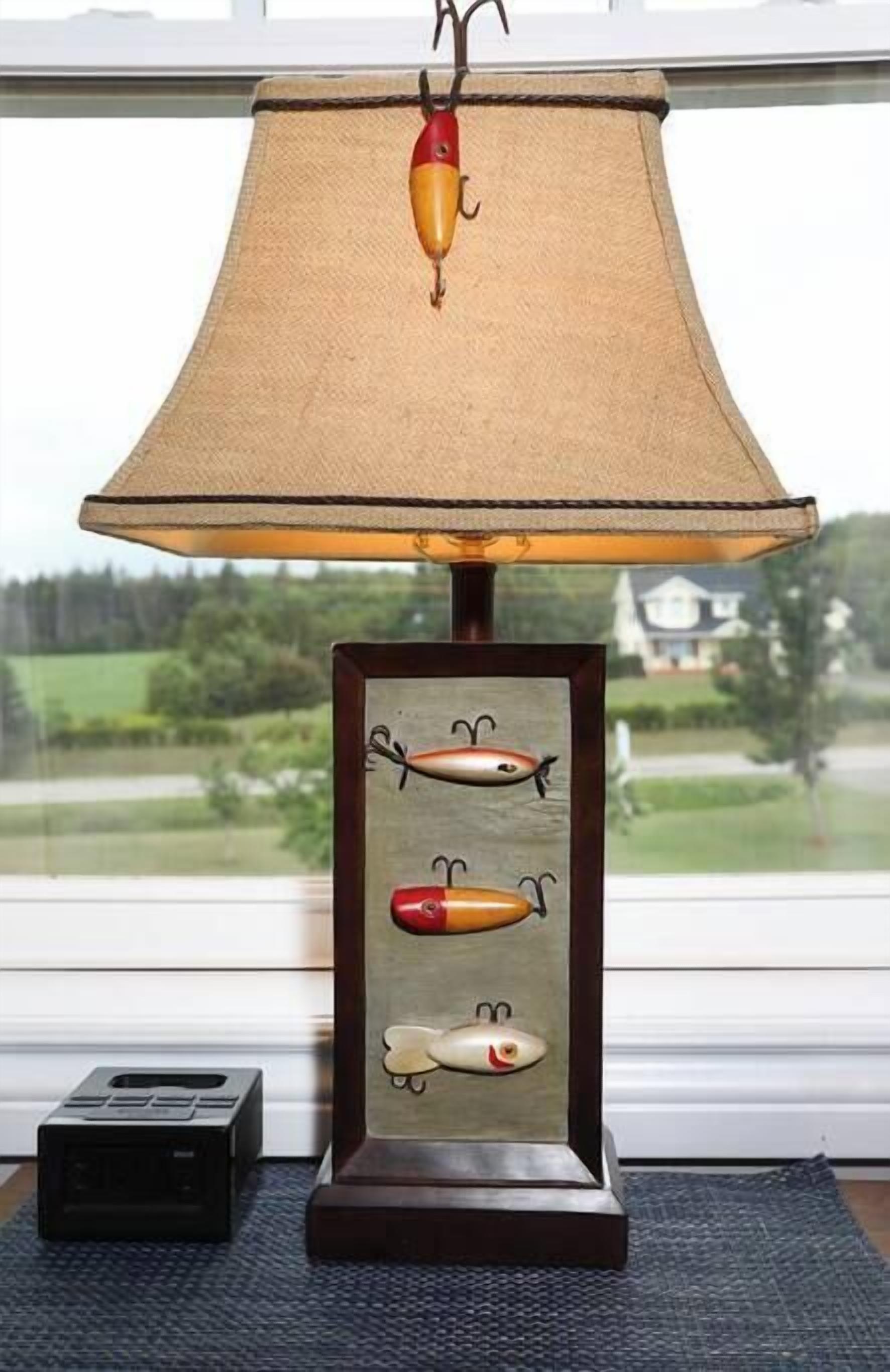 Eine Lampe im Design eines Fischstabes, ein gerahmtes Bild von Fischen und Blick auf ein Haus durch ein Fenster.