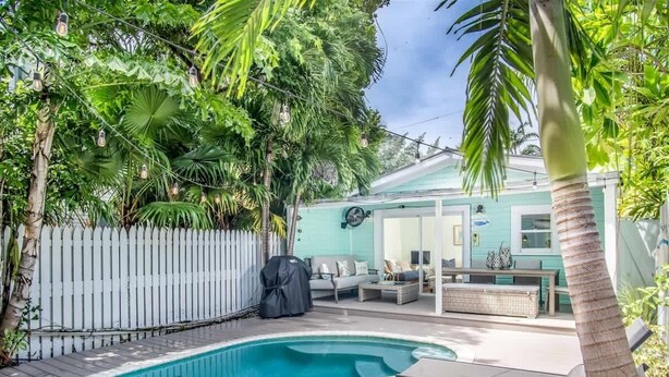 A backyard with a swimming pool, outdoor furniture, and a white picket fence. - Runaway Bills (Key West)