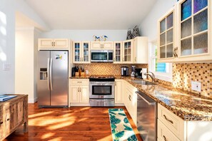A modern kitchen with a refrigerator, oven, microwave, and a tiled backsplash.