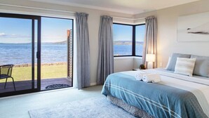 Ein Schlafzimmer mit einem großen Bett, Meerblick und einem Balkon mit einem Stuhl.