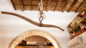 A rustic interior with a wooden ceiling, an arched doorway, and a bed with a wooden headboard.