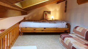 Une chambre à coucher de style loft avec un lit en bois, un canapé, une lampe et une affiche au mur.
