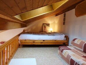 Ein Schlafzimmer im Loft-Stil mit einem Holzbett, einer Couch, einer Lampe und einem Poster an der Wand.