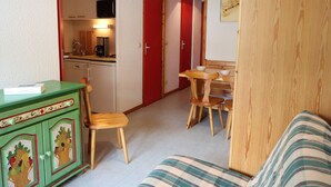 A compact living space with a kitchenette, a dining area, and a sofa.