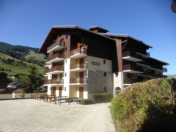 A multi-story hotel with balconies, a stone facade, and a view of the surrounding landscape.