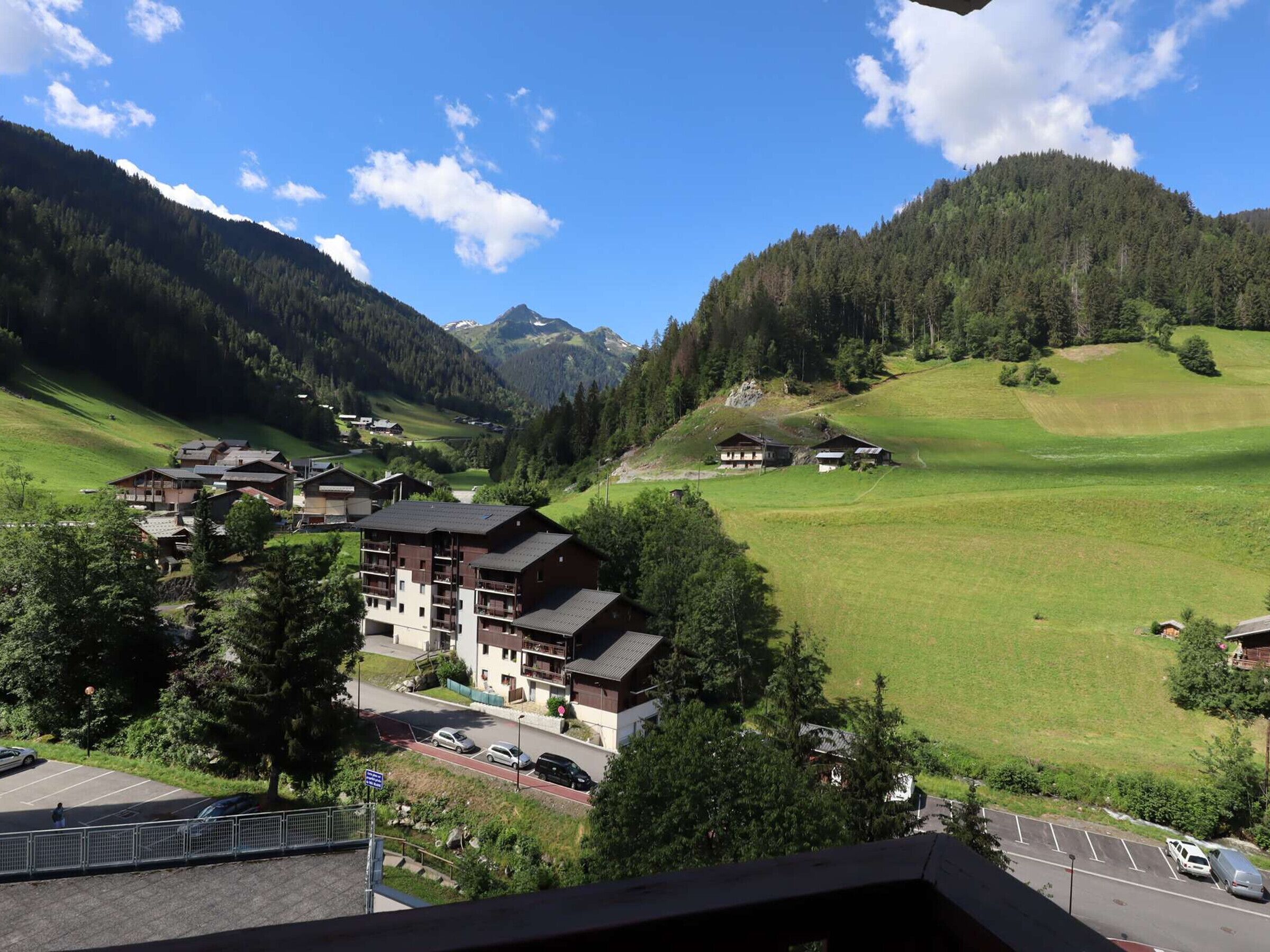 Ein Bergdorf mit Chalets, einem Parkplatz und Blick auf die umliegenden Hügel.