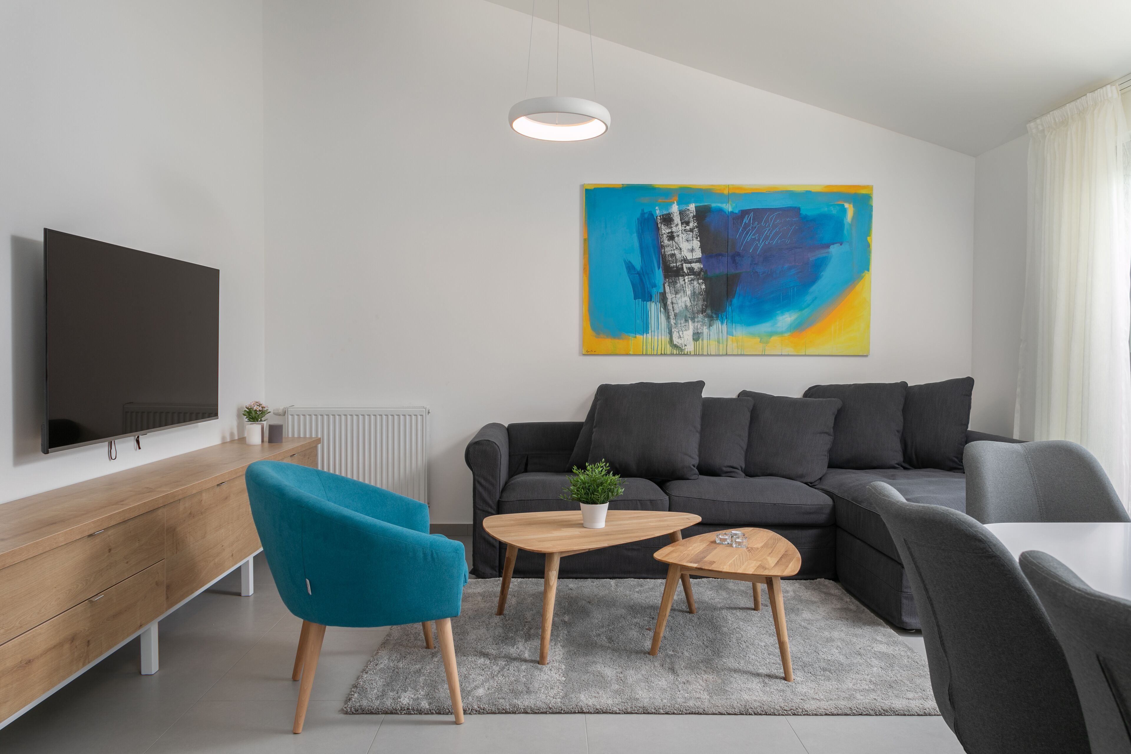 A modern living room with a sofa, a coffee table, a TV, and a painting on the wall.