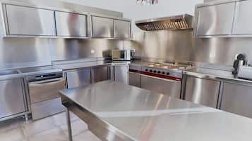 Une cuisine moderne dotée d’appareils électroménagers en acier inoxydable, d’un îlot central et d’un luminaire suspendu rouge.
