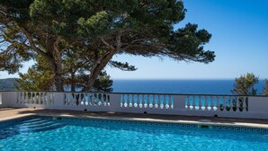 A clear blue pool with a white balustrade, surrounded by trees and overlooking the sea. - Apartamento Buganvilla - Increíbles vistas al mar (San Jaime Mediterráneo)