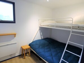 A bunk bed with a blue mattress, a small wooden stool, a white radiator, and a window with blinds. - Cozy 4/5 Pers Apartment with Balcony, Pool Access & Close to Ski - 2 Stars (Arêches-Beaufort)