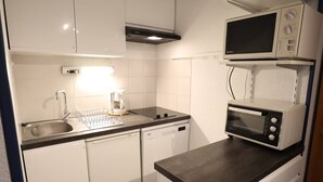 A compact kitchen with a dishwasher, a coffee maker, and a microwave. - Cozy 4/5 Pers Apartment with Balcony, Pool Access & Close to Ski - 2 Stars (Arêches-Beaufort)