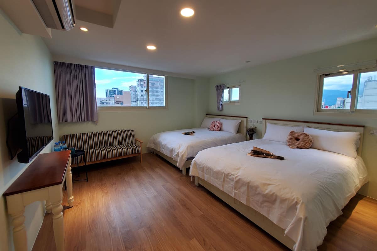 Une chambre d’hôtel avec deux lits, une télévision, un canapé et une vue sur la ville.