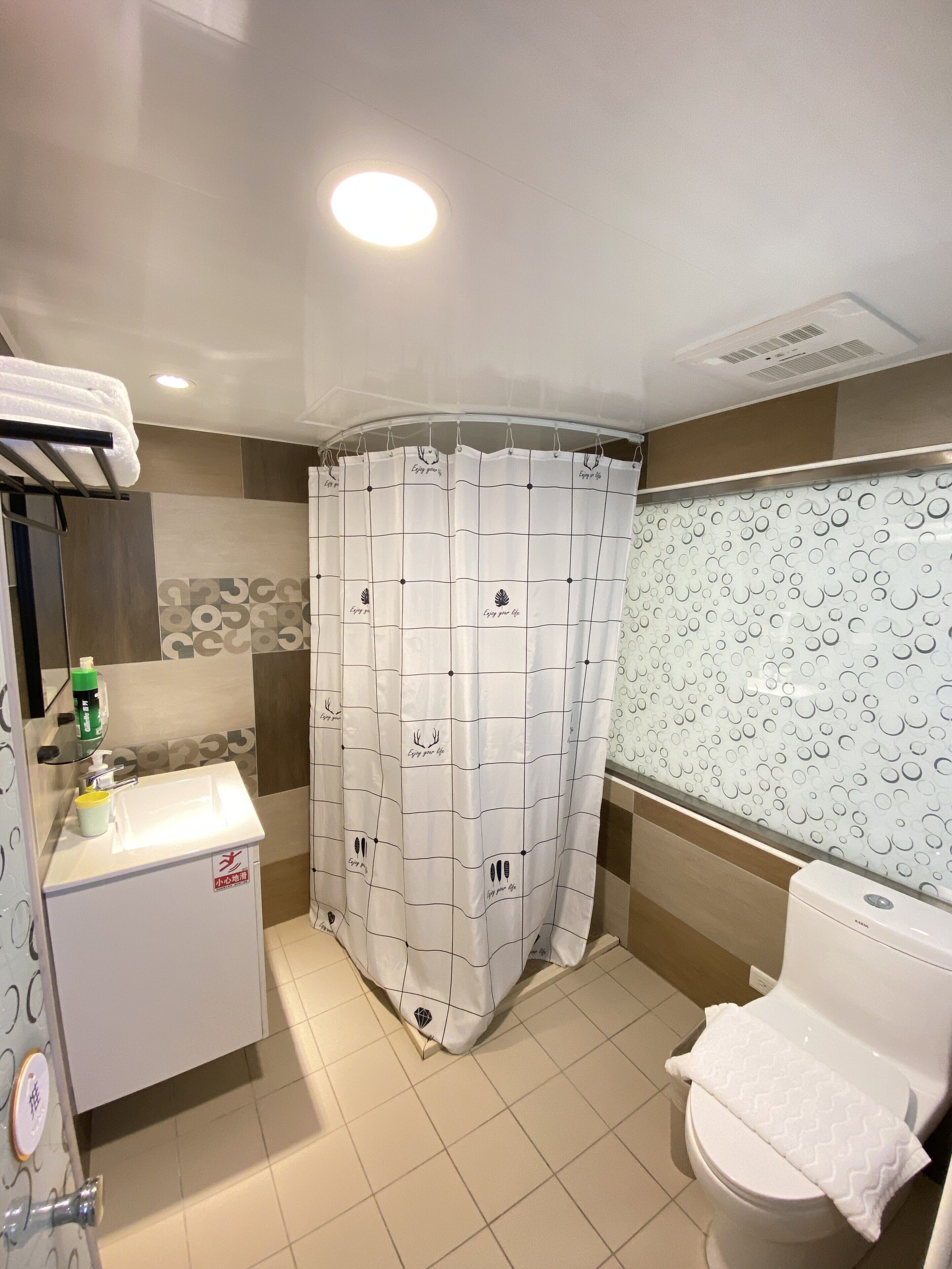 Un baño con cortina de ducha, lavamanos, inodoro y espejo.