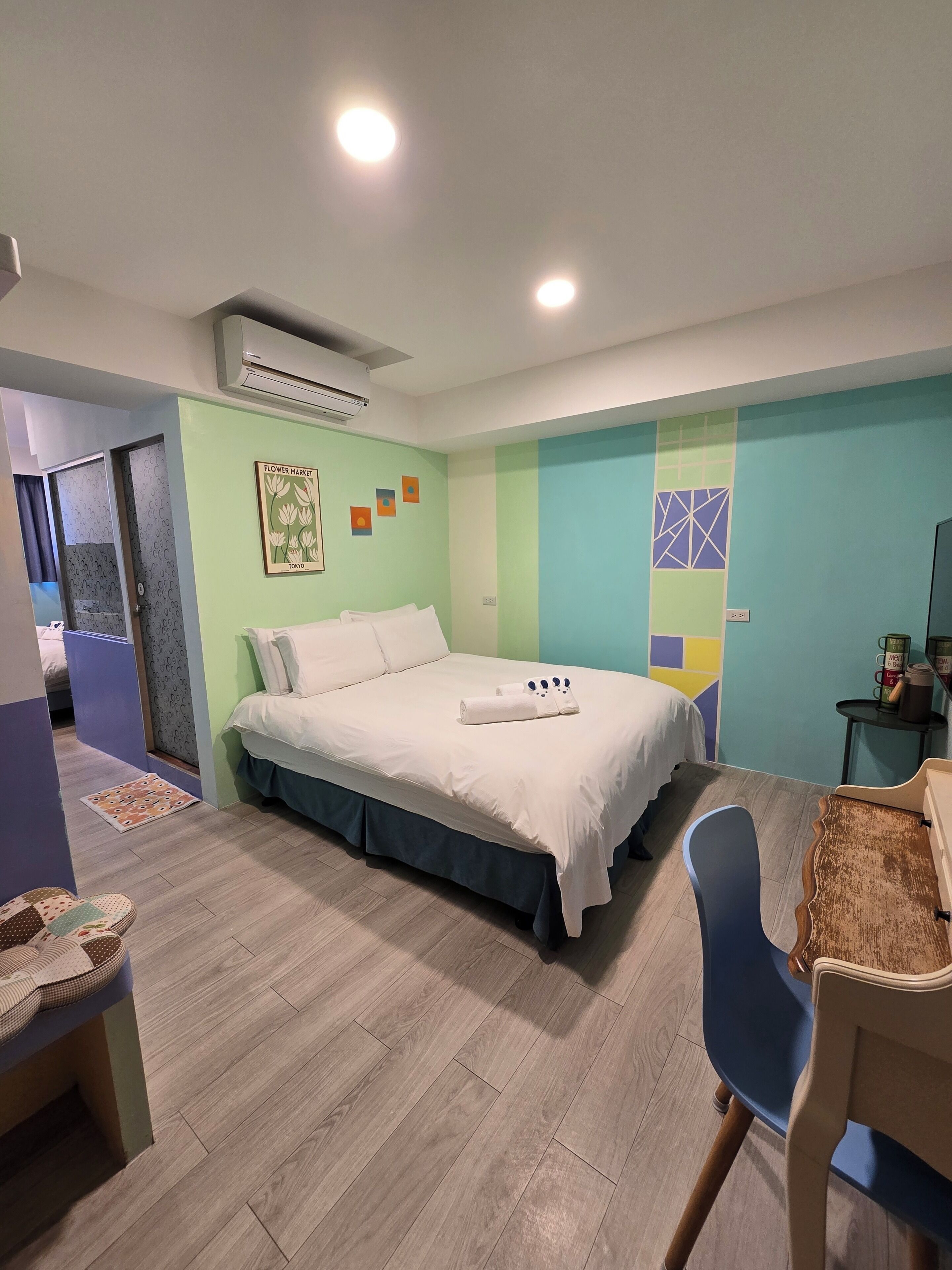 A hotel room with a bed, a desk, a chair, and a small table with a coffee maker.
