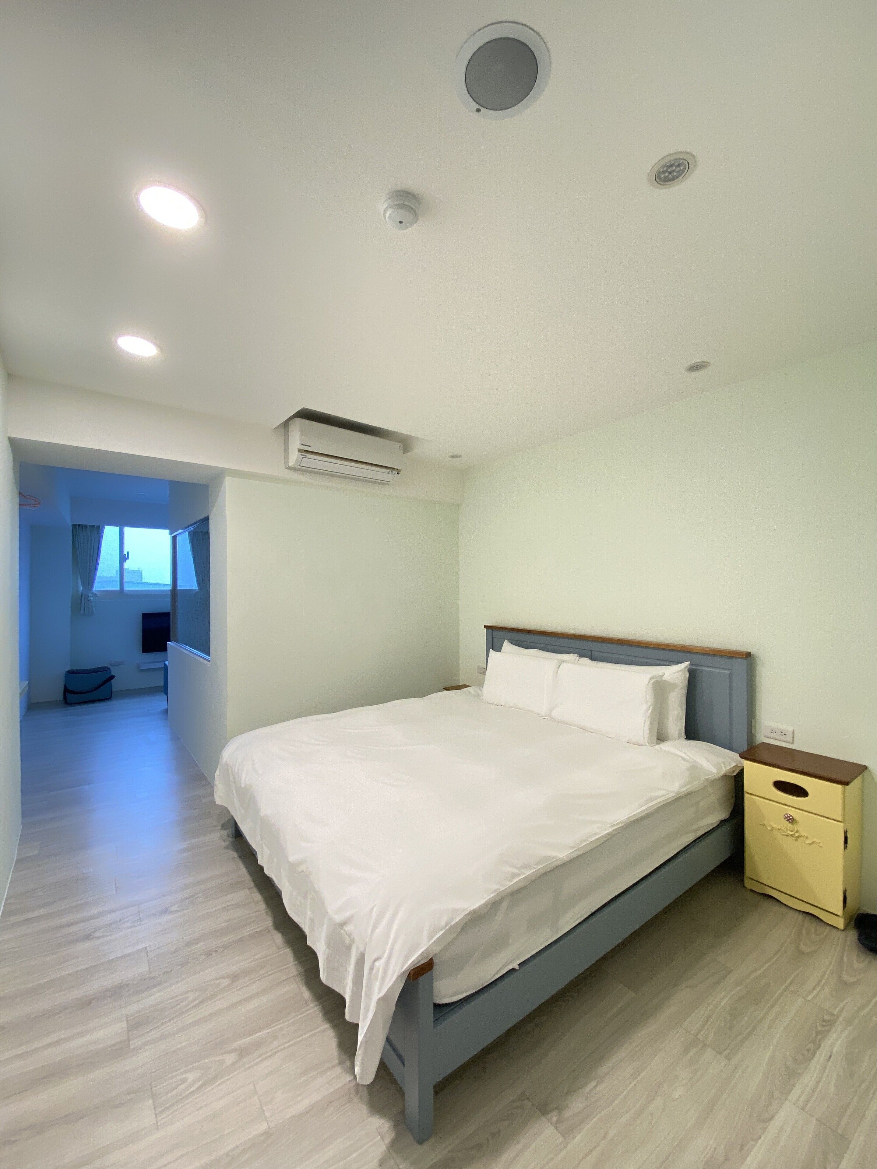 A bedroom with a bed, bedside table, and an air conditioning unit.