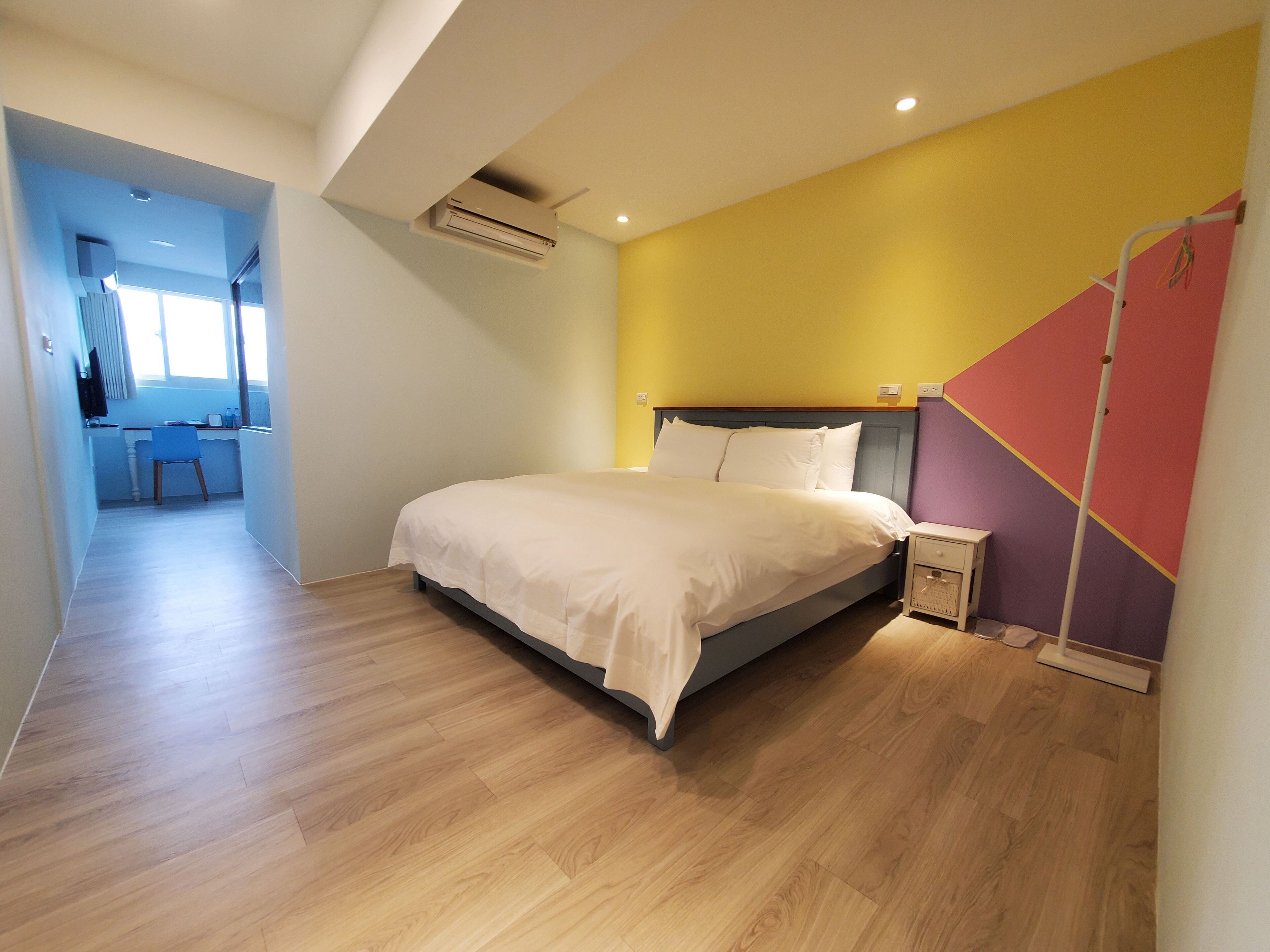 A bedroom with a bed, bedside table, and a desk area with a chair.