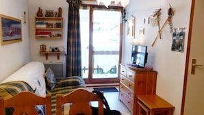 Une petite chambre à coucher, confortable et accueillante, avec un lit, un bureau, une chaise, une commode et un téléviseur.