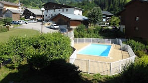 Un quartier résidentiel doté d’une piscine entourée d’une clôture blanche, de maisons et ayant un paysage montagneux en arrière-plan.