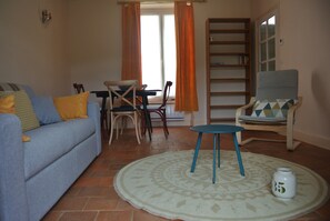 A living room with a sofa, a small table, a chair, a bookshelf, and a patterned rug.