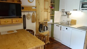 A kitchen with wooden cabinets, a Bosch dishwasher, a sink, and a wooden dining table. - Renovated apartment with pool, near slopes, for 4 people (Arêches-Beaufort)
