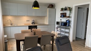 A modern kitchen with grey cabinets, a dining table with chairs, and a black chair in the foreground.