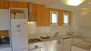 Une cuisine compacte avec des meubles en bois, un four encastré, une cuisinière et un réfrigérateur.