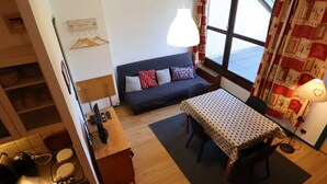 Ein gemütlicher Raum mit einer Couch, einem kleinen Tisch, einer Lampe und einem Fenster mit Vorhängen.
