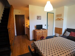 Um quarto com uma cama, uma escrivaninha com televisão, uma cadeira e uma escada.