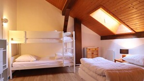 Ein gemütliches Zimmer mit Etagenbett, einem Einzelbett und einem Oberlicht.