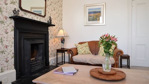 A living room with a fireplace, a sofa, a coffee table, a lamp, and a framed picture on the wall.