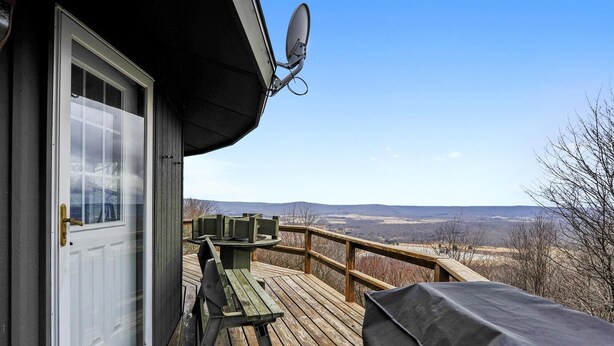 Una terraza de madera con un área de estar cubierta y una puerta que da a una habitación con antena parabólica.