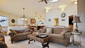 Una sala de estar acogedora con un sofá, sillones, una mesa de centro y un comedor con mesa y sillas.