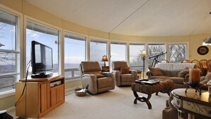Una sala de estar acogedora con ventanas amplias, televisión, asientos cómodos y un telescopio.