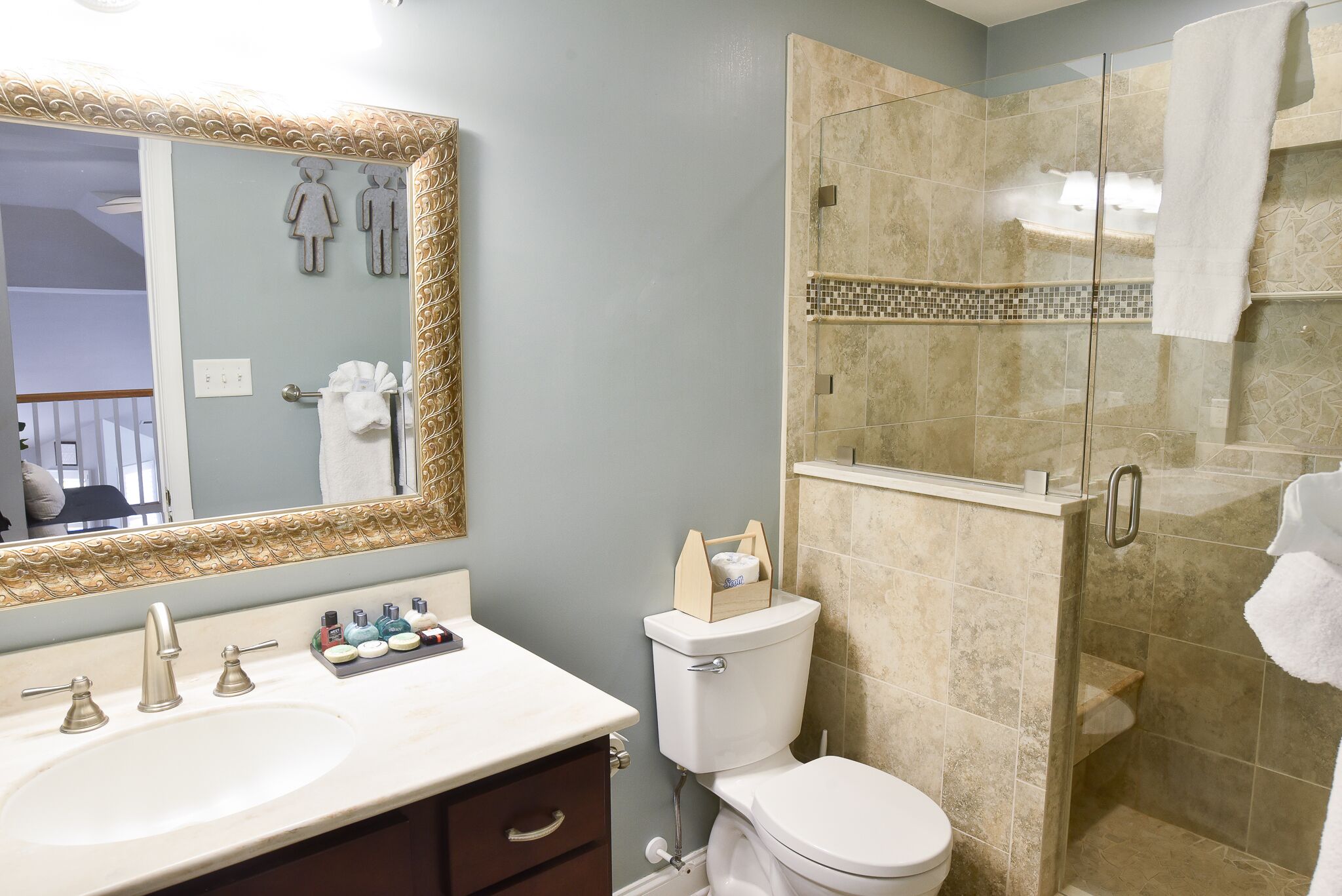 A bathroom with a sink, mirror, toilet, and shower.