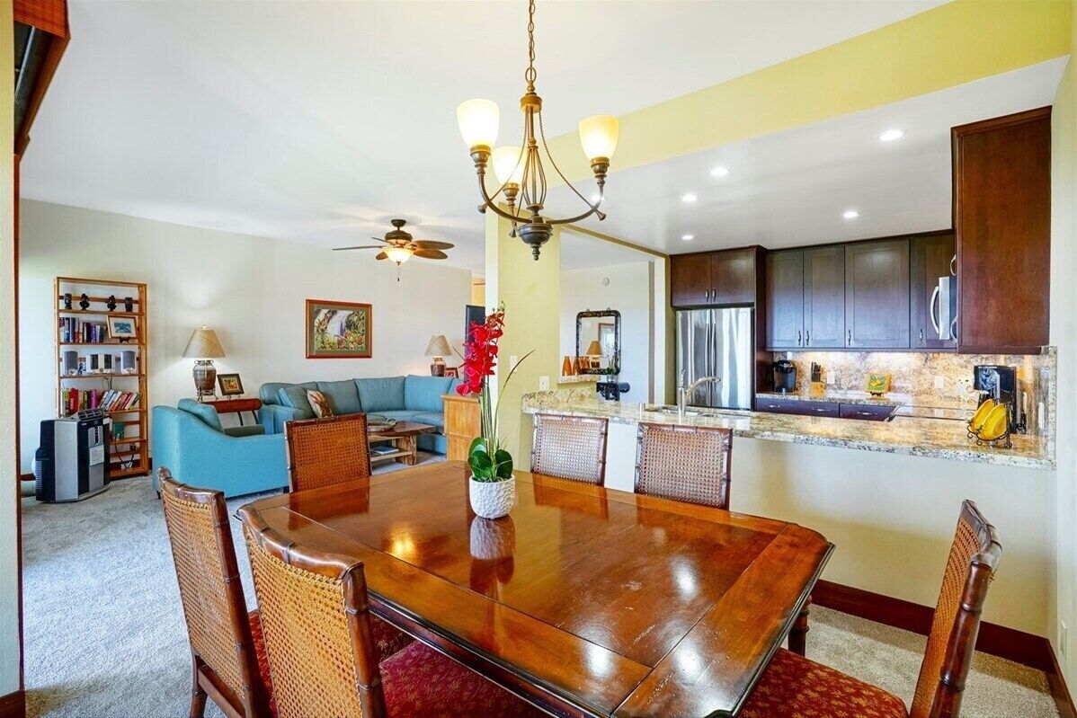 A dining area with a wooden table, wicker chairs, and a chandelier.