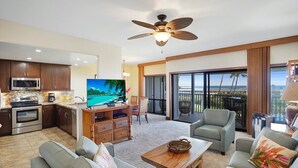 Una sala de estar moderna con televisor de pantalla plana, ventilador de techo y balcón con vistas.