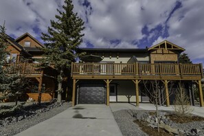 A two-story wooden house with a balcony, a garage, and a driveway.