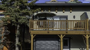 A two-story building with a balcony, a garage, and a tree in front. - Gorgeous south facing 3BDR townhome! (Canmore)