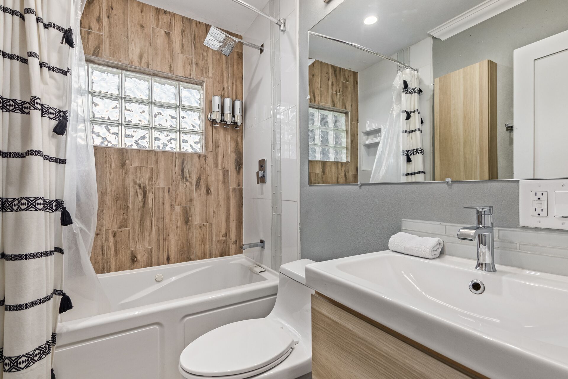 Un baño moderno con un tocador de madera, una bañera y un inodoro.