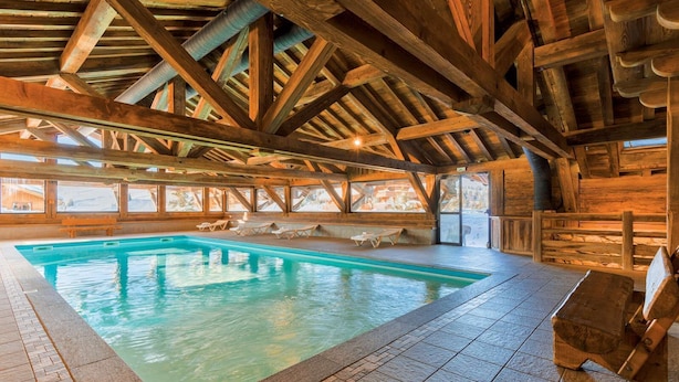 An indoor swimming pool with wooden beams and a tiled floor.