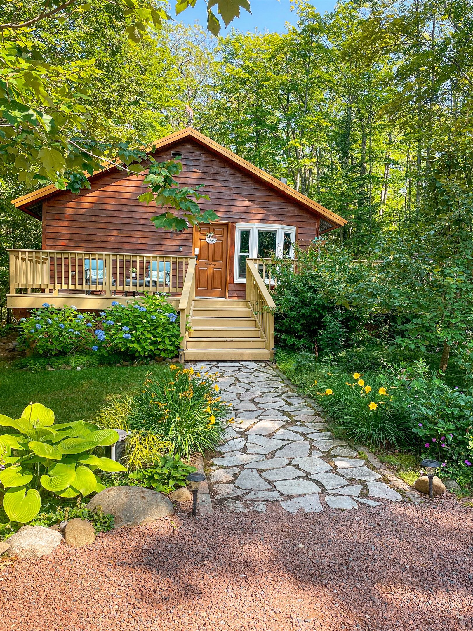 A wooden cabin with a porch and a stone pathway leading to the entrance.