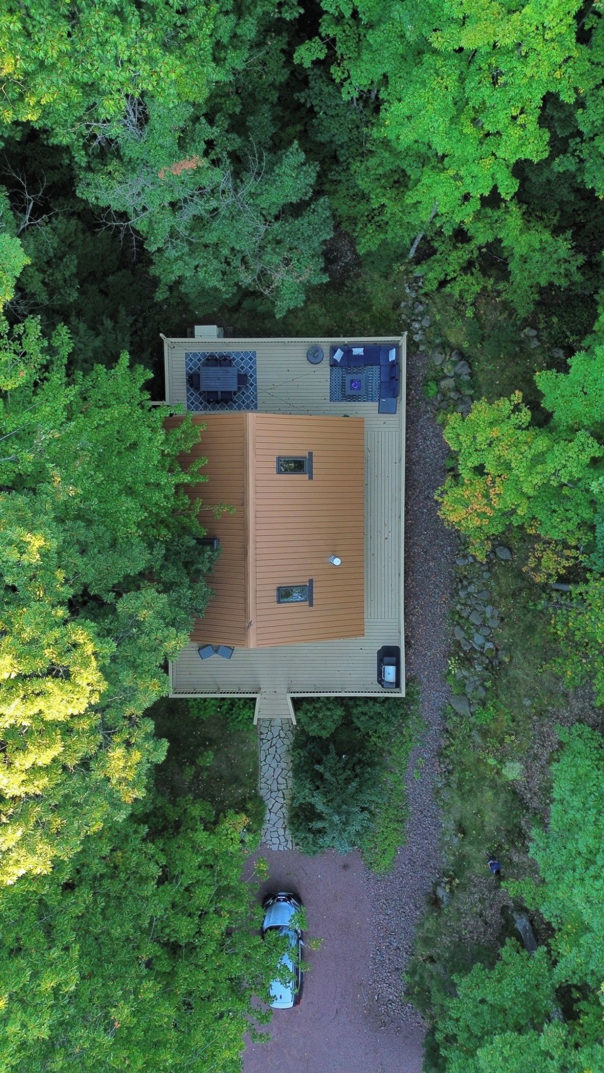 Vue aérienne d’une terrasse en bois, dotée de sièges et d’une petite table, et entourée d’un feuillage verdoyant et luxuriant.