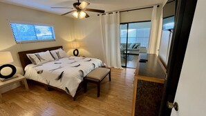 A bedroom with a bed, bedside tables, a desk, a ceiling fan, and a view through a glass door to a living area. - Beautiful Spacious 3 bedroom home near Clearwater Beach, Pet friendly! (Clearwater)