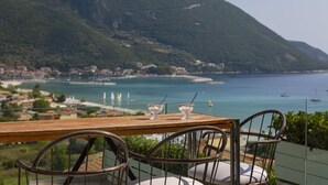 A table with two chairs overlooking a coastal landscape with a mountain and a view of the sea. - Villa Mare with Private Pool and Sea Views (Vasiliki)