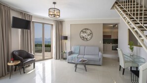 A modern living room with a sofa, armchair, and coffee table, a staircase, and a view of the outdoors. - Villa Mare with Private Pool and Sea Views (Vasiliki)