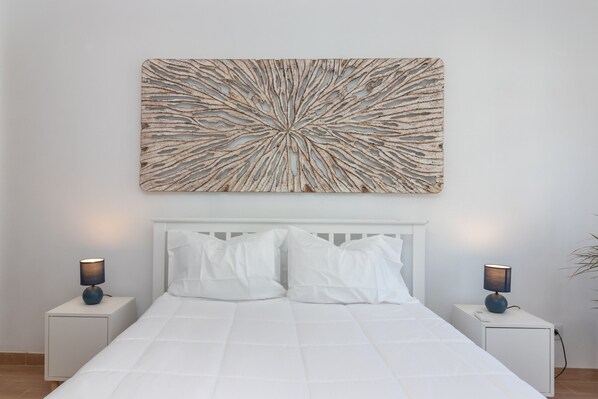 A bedroom with a white bed, white nightstands, and a wall-mounted abstract art piece. - Casa Angelica - Near beach, rooftop terrace & stunning views (Carvoeiro)