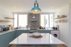 A modern kitchen with a central island, built-in appliances, and a hanging light fixture. - Casa Angelica - Near beach, rooftop terrace & stunning views (Carvoeiro)